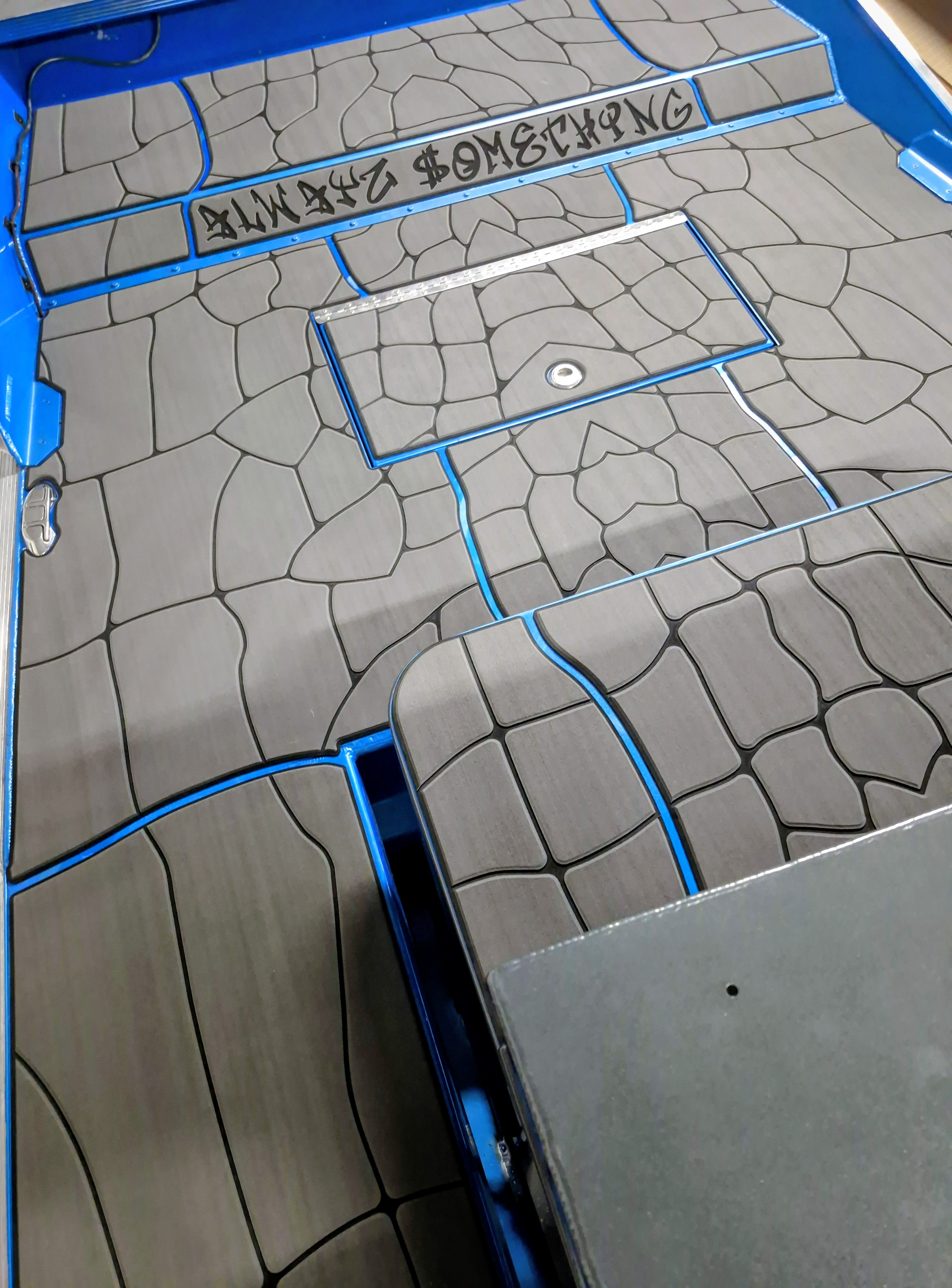 Gray FlexDek boat decking installation on a blue boat with custom routed deck panels